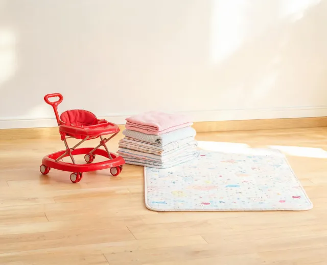 Baby walker beside nursery textiles